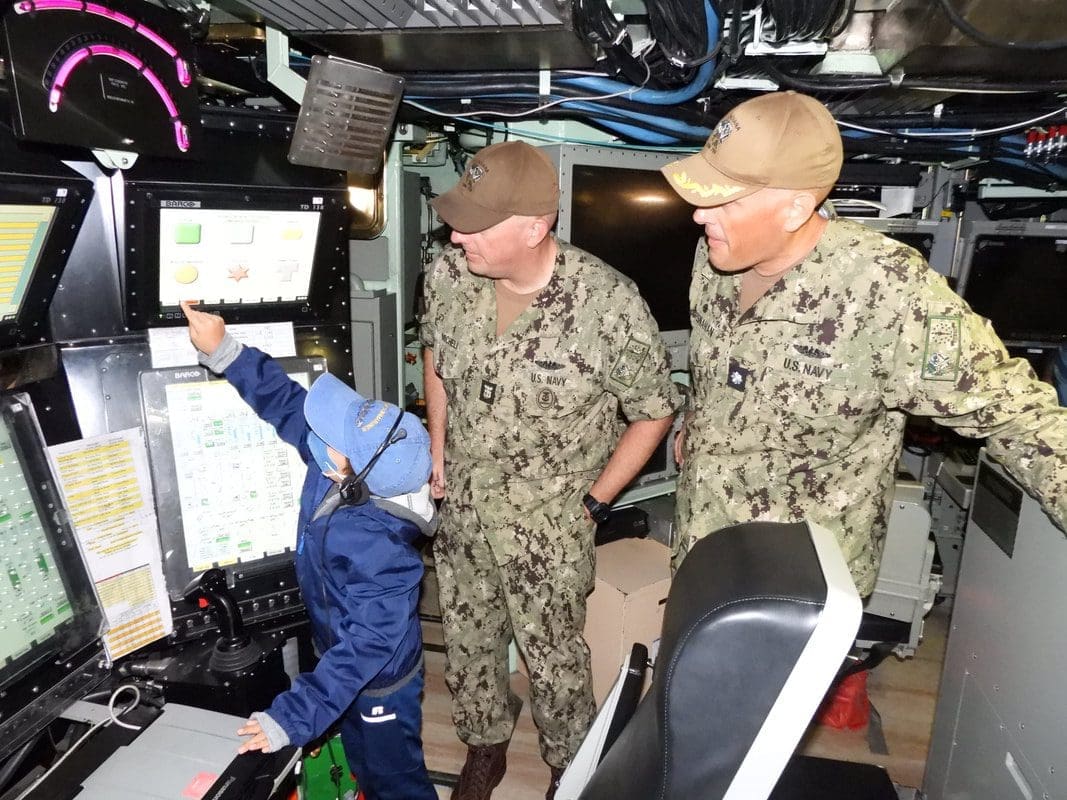 Child and sailors at control panel.