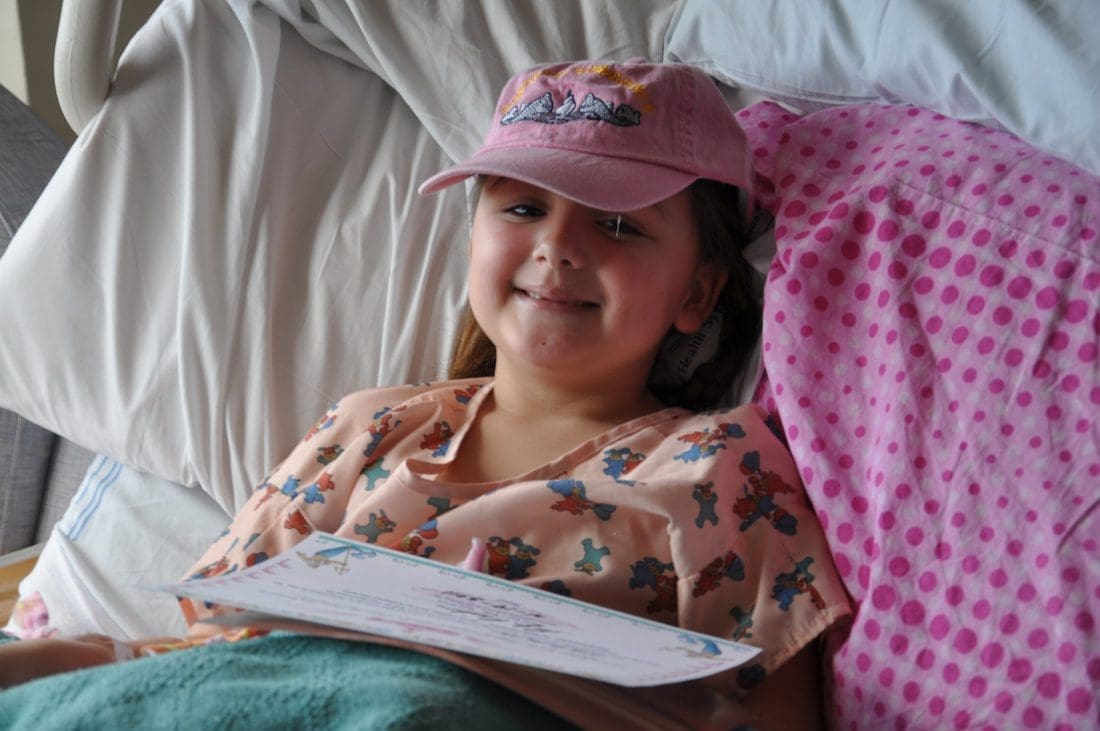 Child in bed wearing a pink cap.