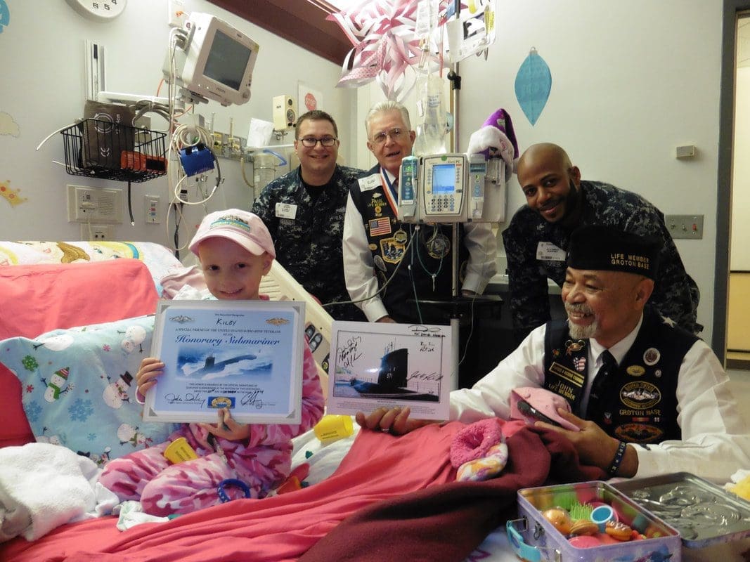 Child in hospital with military visitors.