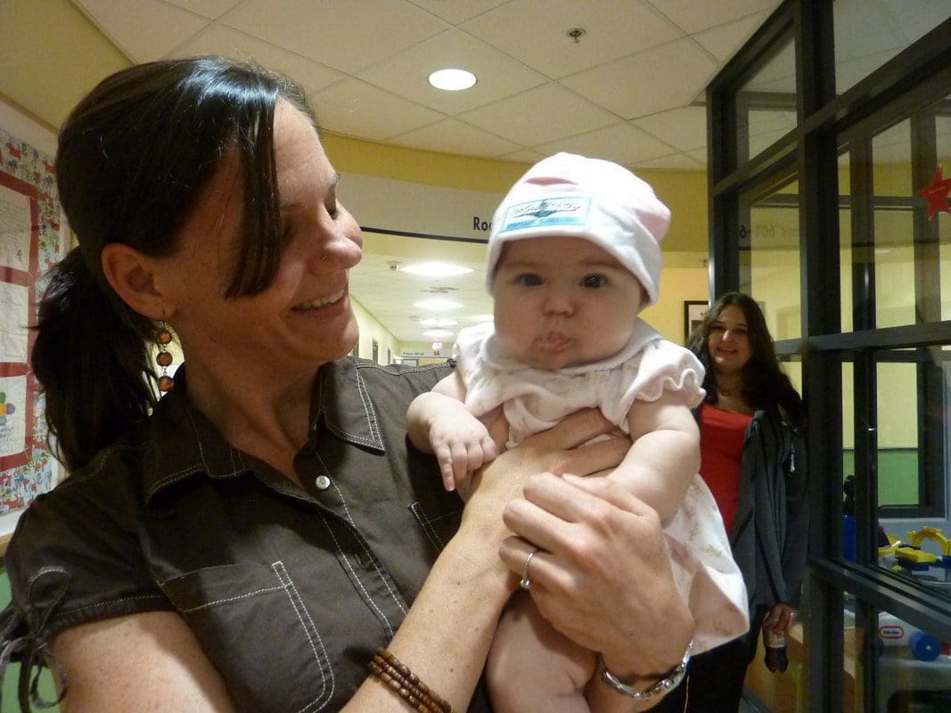 Woman holding a baby in a hallway.
