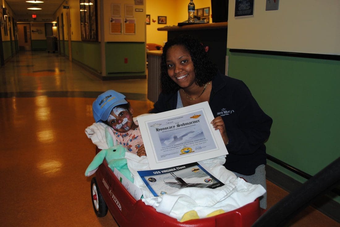 Child in wagon with certificate and woman.