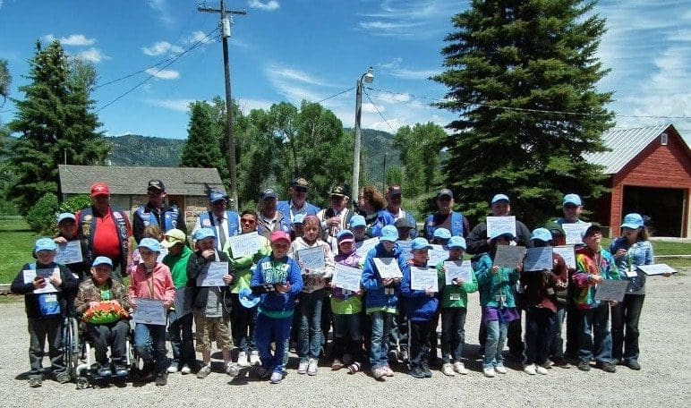 Group of children holding certificates outdoors.