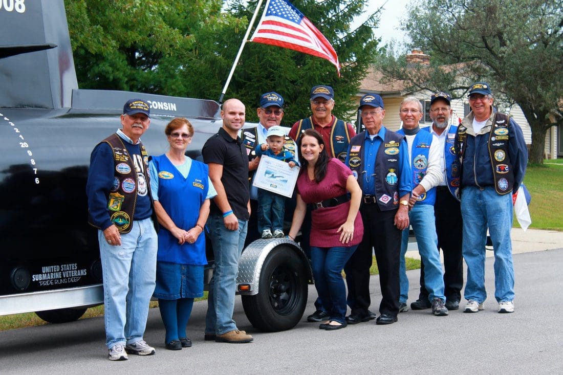Group posing with American flag, outdoors.