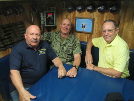 Three men sitting around a poker table in a cozy room.